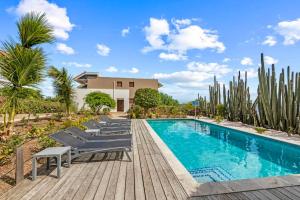 a swimming pool with lounge chairs next to a house at Boca Gentil Bayside 10 in Jan Thiel