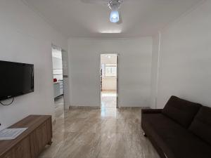 ein Wohnzimmer mit Couch und Flachbildfernseher in der Unterkunft Apê vista mar pé na areia Guilhermina in Praia Grande