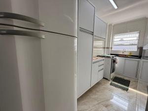 eine Küche mit weißen Schränken und einem Kühlschrank in der Unterkunft Apê vista mar pé na areia Guilhermina in Praia Grande