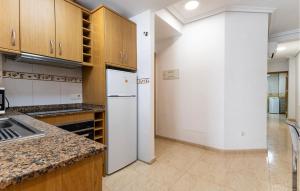 a kitchen with wooden cabinets and a white refrigerator at Awesome Apartment In Torrevieja in Torrevieja