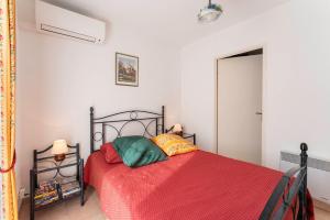 Schlafzimmer mit einem Bett mit einer roten Bettdecke in der Unterkunft Villa climatisée avec piscine in Vaison-la-Romaine + 22 Fotos