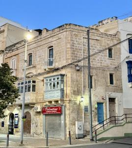 an old brick building with a balcony on a street at Mediterranea Waterfront house - By Valletta Ferry & Free Parking in Cospicua