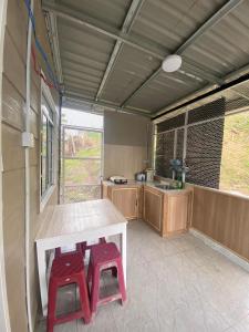 a kitchen with a table and two red stools at Dtwinnie homestay lalita house in Kundasang