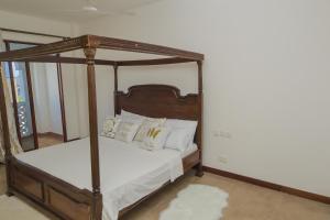 a bedroom with a canopy bed with white pillows at Victorious Kings Homes in Mtwapa