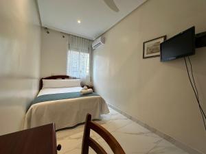 sypialnia z łóżkiem i telewizorem na ścianie w obiekcie Hostal Villamañez w Madrycie