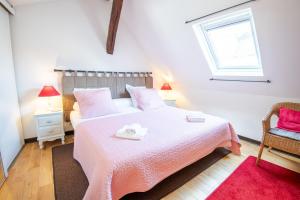 a bedroom with a bed with pink sheets and a window at La Petite Hermine in Amboise