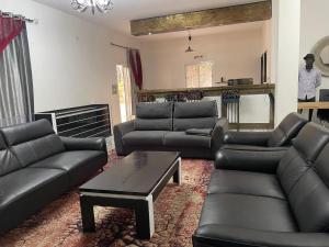 sala de estar con sofás de cuero negro y mesa en Villa Lydia Saly, en Saly Portudal