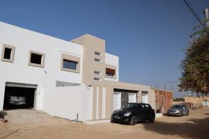 a black car parked in front of a white building at Al Yasmine residence in Douz