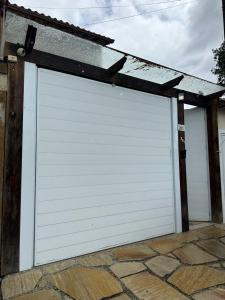 a white garage door with a roof on top at Casa Caborê, Paraty-RJ in Paraty