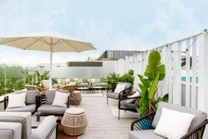an outdoor patio with chairs and tables and an umbrella at Radisson Collection Hotel, Magdalena Plaza Sevilla in Seville