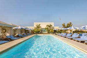 a pool with chairs and umbrellas at a hotel at The Maybourne Beverly Hills, Maybourne in Los Angeles