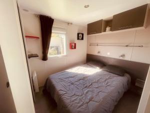 a small bedroom with a bed and a window at Mobi Home Palmiers 2 in Valras-Plage +30 photos