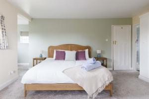 a bedroom with a large bed with purple pillows at Charming Beach Getaway - Spacious 4BR sunny garden in West Wittering