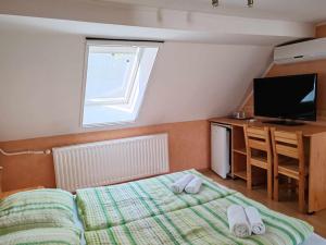 a small bedroom with a bed and a television at Czérna Vendégház in Tata