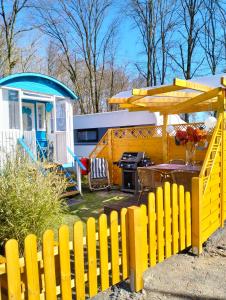 einen gelben Zaun mit einem Picknicktisch und einem Grill in der Unterkunft Cottage-Irina in Brandenburg an der Havel + 12 Fotos