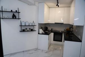 a kitchen with white cabinets and marble floors at Mostar Comfort Suites in Mostar