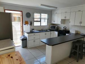 a kitchen with white cabinets and a black counter top at VanZylsRus in Pearly Beach