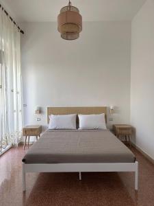 a white bedroom with a large bed with two tables at Giardino del Geco in Brindisi +40 photos