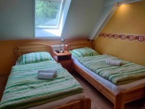two twin beds in a room with a window at Czérna Vendégház in Tata