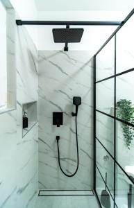 a shower in a bathroom with white marble walls at Apartman Petra s pogledom na more in Banjol