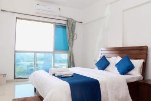 a bedroom with two beds with blue pillows and a window at Zenith Homes - Boomerang Suites in Mumbai