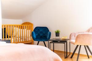 a bedroom with a crib and a blue chair at Apartman Petra s pogledom na more in Banjol
