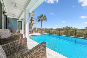 a swimming pool with chairs and a house at 8 Sea Front, Oceanfront Estate, Pool, Game Room, Elevator in Hilton Head Island