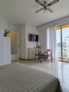 um quarto com uma cama e uma mesa com uma ventoinha de tecto em Bright and spacious seaside studio em Roquebrune-Cap-Martin