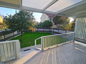 a porch with a white railing and a green yard at Hóvirág Apartman in Hódmezővásárhely