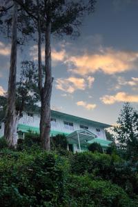 um edifício com duas árvores em frente em Golden Cherry Homestay em Kodaikānāl