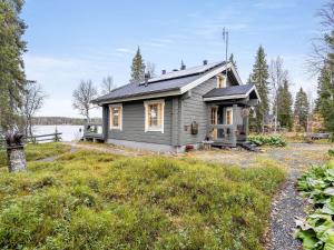 ein kleines graues Haus auf einem Feld neben einem See in der Unterkunft Holiday Home Rukaniemen kontio by Interhome in Ruka