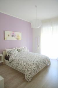 a white bedroom with a bed with a flowery bedspread at B&B BuonaLuna in Salerno