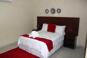 a bedroom with a large bed with a red and white blanket at Phendulani Lodge & Park in Calcutta +20 photos