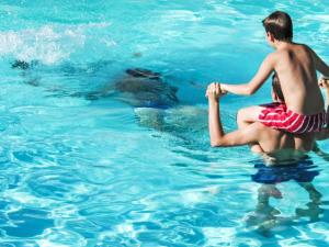 two boys playing in the water with a bear at Apartment Grand Balcon- Piscine et proche du Port by Interhome in Arzon