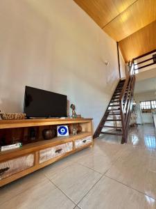 a living room with a television and a staircase at Refugio Brisa do Campo - IG - SOLAR DO CAMPO in Iguaba Grande