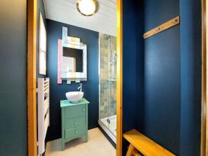ein Badezimmer mit blauen Wänden und einem Waschbecken und einem Spiegel in der Unterkunft Holiday Home Charme de la Petite Bosse by Interhome in LʼÉpine