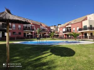 a swimming pool in the middle of a yard with buildings at Comfortable penthouse in Islantilla golf in Lepe