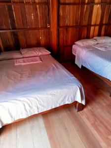 two beds in a room with wooden walls at Cabaña la ira in Santa Maria Huatulco
