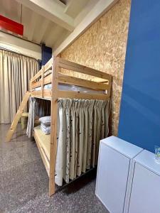 a bunk bed in a room next to a wall at Miaoli Sanyi Travelling Homestay in Sanyi