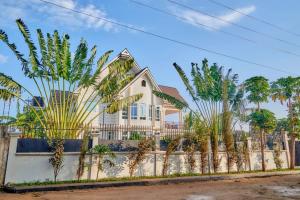 a house with palm trees in front of a fence at Lake duluti serenity villas in Arusha
