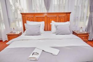 a large white bed with a wooden headboard and white pillows at Lake duluti serenity villas in Arusha