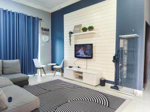 a living room with a couch and a tv on a wall at Homestay Hillview in Selising