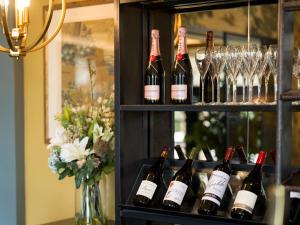 a shelf filled with bottles of wine and glasses at The Kings Arms in Christchurch