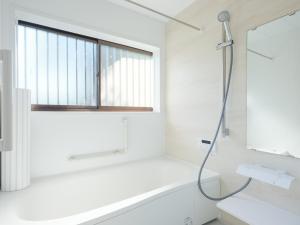 a white bathroom with a bath tub and a window at 薬医門の宿 in Katori