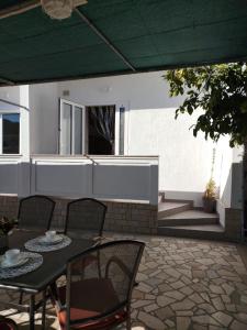 a patio with a table and chairs and a building at Cute apartment Arba in Rab