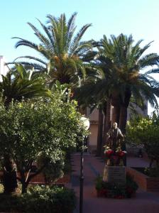 a statue of a man in a courtyard with palm trees at Hotel Sylesia in Letojanni