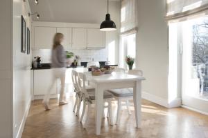 una mujer en una cocina con una mesa blanca y sillas en von Deska Townhouses - White House en Hamburgo