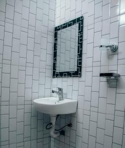 a white tiled bathroom with a sink and a mirror at victorious chillzone hostel in Nkoanrua