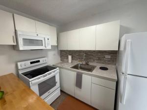 a kitchen with white cabinets and a sink and a refrigerator at A1-tg Family Oriented Stay in Caguas