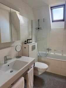 a bathroom with a sink and a toilet and a tub at Haus Zum Park - The apartment in Baden